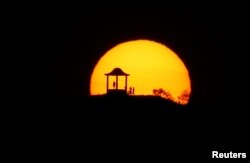 Siluet manusia tampak saat matahari terbenam di 'El Mirador de la Alemana' di tengah gelombang panas musim panas yang menerpa Spanyol di Malaga, Spanyol Selatan, 24 Juli 2019.