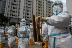 Petugas kesehatan mengenakan APD memainkan angklung, alat musik tradisional yang terbuat dari bambu untuk merayakan ulang tahun pertama Rumah Sakit Darurat COVID-19 Wisma Atlet di Jakarta, 23 Maret 2021. (Foto: Antara/M Risyal Hidayat via REUTERS)