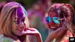 A foreign tourist, left and an Indian smear colored powder on each other as they celebrate Holi, the festival of colors in Hyderabad, India, March 12, 2017.