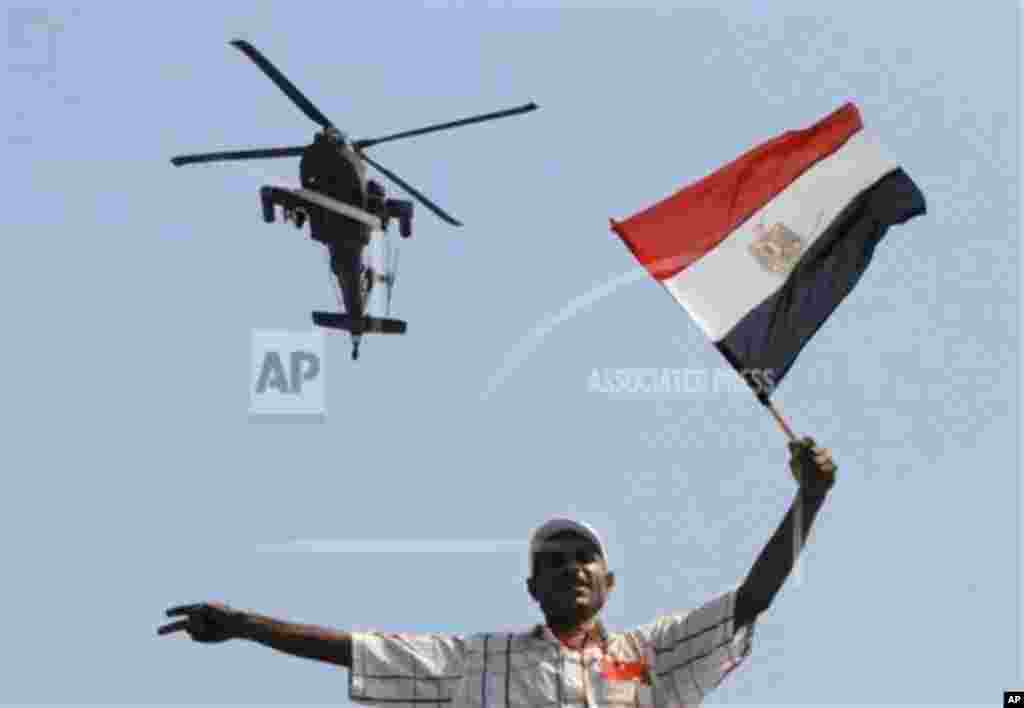 A protester holds an Egyptian national flag as he and others attack the Muslim Brotherhood headquarters in the Muqattam district in Cairo, July 1, 2013.