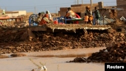 Family members rest in the remains of their house destroyed by floods caused by heavy rains in Khartoum Aug. 6, 2013.