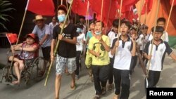 Villagers including schoolchildren take part in a protest march, demanding the release of their village chief Lin Zuluan, in Wukan, in China's Guangdong province, June 21, 2016. 