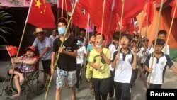 Villagers including schoolchildren take part in a protest march, demanding the release of their village chief Lin Zulian, in Wukan, in China's Guangdong province, June 21, 2016. 