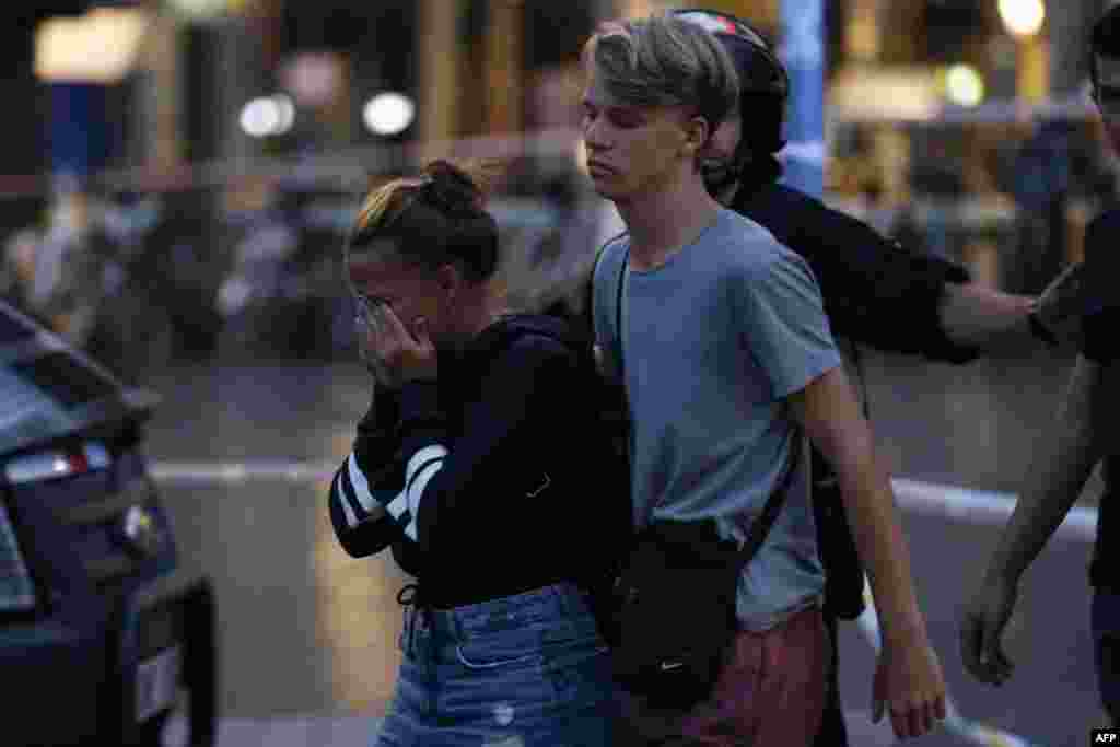 A woman cries as she and a man are escorted by Spanish police outside a cordoned off area after a van plowed into a crowd on the Las Ramblas avenue in Barcelona, Aug. 17, 2017.