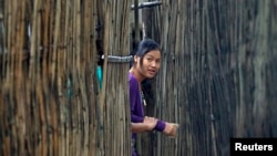 FILE - A refugee who fled Myanmar watches from behind a bamboo wall of a stilt house at Mae La refugee camp, near the Thailand-Myanmar border in Mae Sot district, Tak province, north of Bangkok, on July 21, 2014.