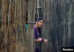 FILE - A refugee who fled Myanmar watches from behind a bamboo wall of a stilt house as Thai authorities conduct a census at Mae La refugee camp, near the Thailand-Myanmar border in Mae Sot district, Tak province, Thailand. Many refugees are hopeful about