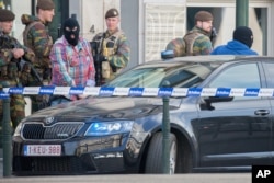 Police officers guard the entrance as a car arrives at the federal court building in Brussels on Thursday, June 9, 2016.