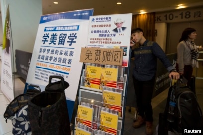 Seorang mahasiswa China berbicara di telepon di belakang poster iklan pendidikan luar negeri usai ujian SAT (Scholastic Assessment Test) di AsiaWorld-Expo, Hong Kong, 2 November 2013. SAT adalah pra syarat mendaftar ke perguruan tinggi AS. (Foto: Reuters)