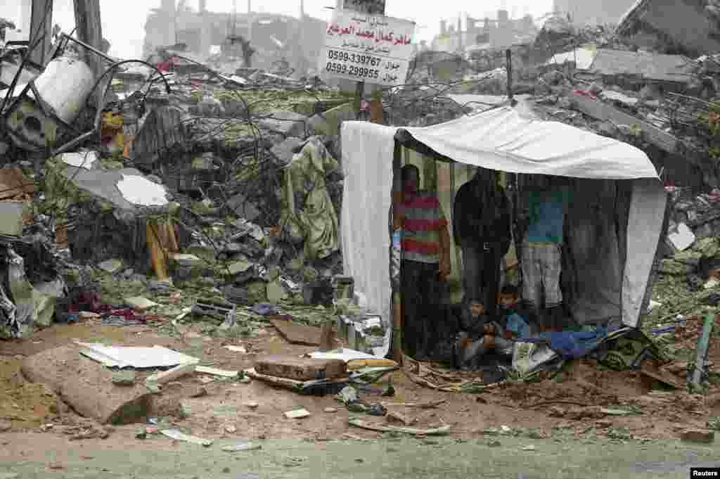 Palestinians take cover from rain inside a makeshift shelter near the ruins of their houses, which witnesses said were destroyed during a seven-week Israeli offensive, in the east of Gaza City. 
