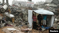 Palestinians take cover from rain inside a makeshift shelter near the ruins of their houses, that witnesses said were destroyed during a seven-week Israeli offensive, in the east of Gaza City, October 19, 2014. 