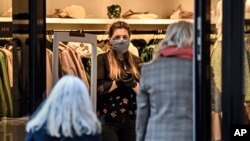 A saleswoman waits for customers in a shop as many smaller stores are allowed to open in Essen, Germany, Monday, April 20, 2020. Europe's biggest economy, starts reopening some of its stores and factories after weeks of lockdown due to the new coronavirus