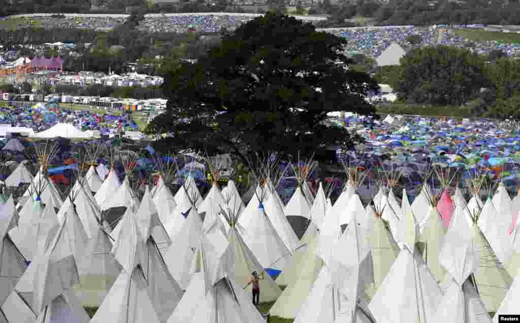 A festival goer erects tipis at Worthy Farm in Somerset during the first day of the Glastonbury Festival, Britain. 