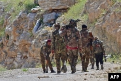 FILE - Fighters with the Syrian Democratic Forces (SDF) patrol near the town of Baghuz, in the Syrian countryside, March 20, 2019.