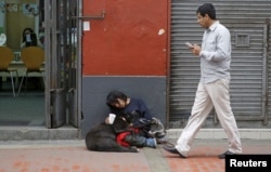 Arturo Tello sleeps with his dog, Negrita Rubi, as he asks for money in downtown Lima, Sept. 23, 2015.