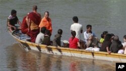 A boat carrying last batch of Burmese refugees back home cruises on the Moei river in Mae Sot, Thailand, 10 Nov 2010
