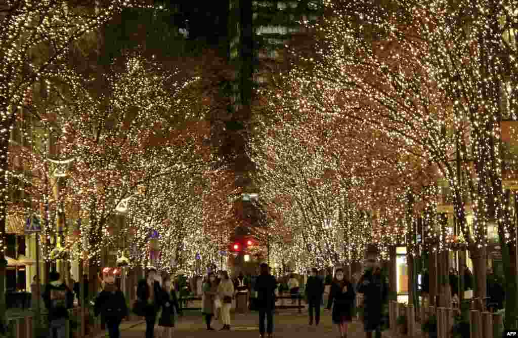 People walk under winter-themed illumination, lit by approximately 1.2 million &quot;champagne gold&quot; LED lights in the Marunouchi business district of Tokyo, Japan.