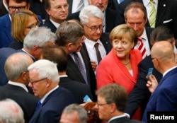 FILE - German Chancellor Angela Merkel prepares to vote during the session of Germany's parliament, the Bundestag, in Berlin, July 17, 2015.