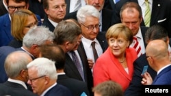 Chancellor Angela Merkel prepares to vote during the session of Germany's parliament, the Bundestag, in Berlin, July 17, 2015. 