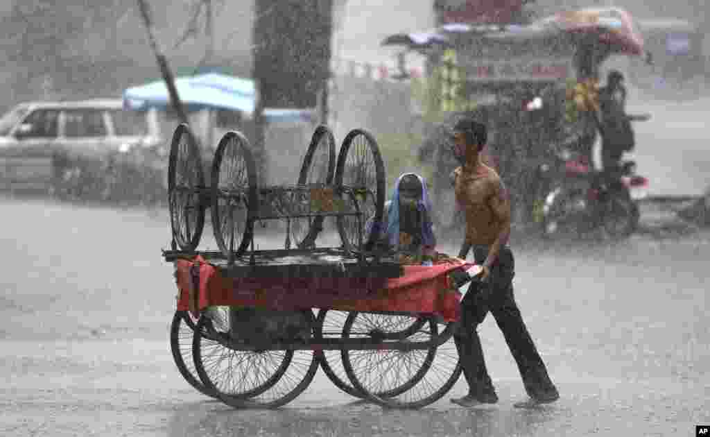 A man pushes a handcart in heavy rain in Jammu, India.