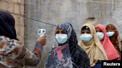 Vaccinators wear protective masks as they get their temperature checked, during an anti-polio campaign, in a low-income neighborhood as the spread of the coronavirus disease continues, in Karachi, Pakistan, July 20, 2020.