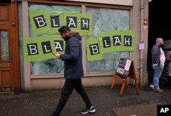 FILE - A man walks past a shop with the phrase used by climate activist Greta Thunberg on it's windows as a protest organized by the Cop26 Coalition passes by in Glasgow, Scotland, Nov. 6, 2021.