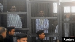 FILE - Political activists Ahmed Maher (R), Ahmed Douma (C) and Mohamed Adel, founder of 6 April movement, look on from behind bars in Abdeen court in Cairo, December 2013.