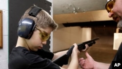 FILE - An instructor shows a boy, 12, how to hold a shotgun at a shooting range in Houston, Texas, May 19, 2013.