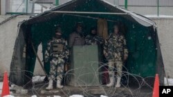 Indian paramilitary soldiers take shelter from snow as they stand guard in Srinagar, Indian controlled Kashmir, Jan. 25, 2017. Four members of a family and an Indian soldier were killed Wednesday when they were buried by two separate avalanches in the Himalayan region of Kashmir, officials said. 