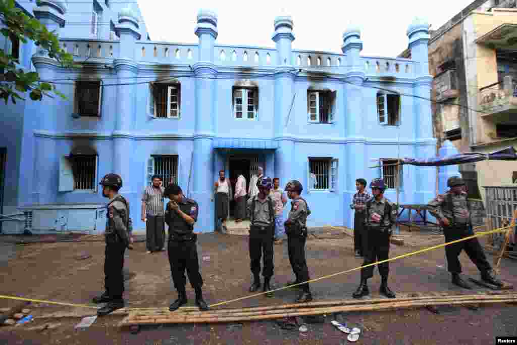 Police stand in front of a mosque and school dormitory that were damaged by a fire in Rangoon, Burma, April 2, 2013. 