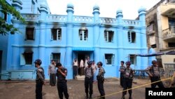 Police stand in front of a mosque and school dormitory that were damaged by a fire in Rangoon, Burma, April 2, 2013. 