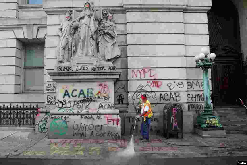 A worker washes the sidewalk to remove graffitis after police dismantled the &quot;City Hall Autonomous Zone&quot; that was in support of the Black Lives Matter movement in the Manhattan borough of New York City.