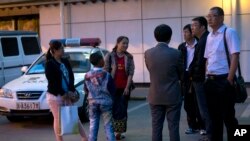 Relatives of Chinese passengers onboard the missing Malaysia Airlines Flight 370, left, talk to Chinese officials, right, outside a hotel as the Malaysia Airlines ceased to provide the hotel accommodation for the relatives in Beijing Friday, May 2, 2014