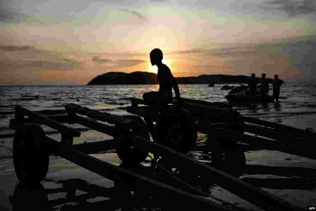 A boy sits on trailers during sunset at Cenang beach in Malaysia&#39;s popular island of Langkawi.