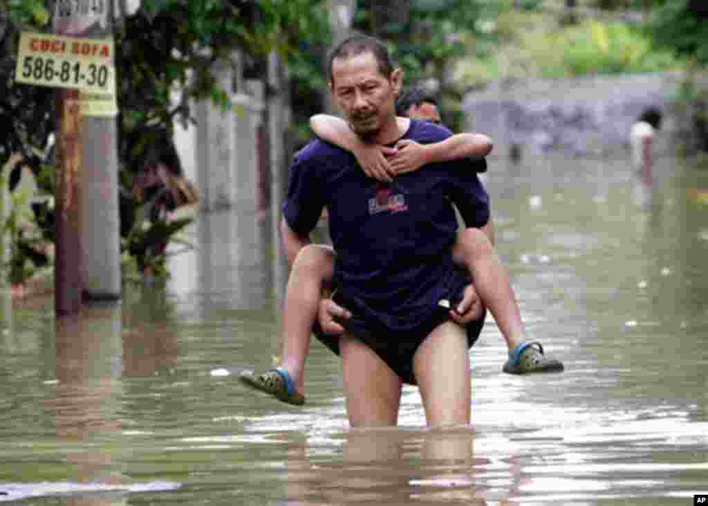 An Indonesian man carries his son through a flooded neighborhood in Tangerang on the outskirts of Jakarta, Indonesia, Wednesday, Oct. 27, 2010. (AP Photo/Tatan Syuflana)