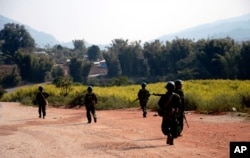 FILE - Myanmar army soldiers carrying weapons patrol on a road as part of operations against ethnic rebels, in Kokang, northeastern Shan State, more than 800 kilometers (500 miles) northeast of Yangon, Myanmar.