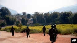 FILE - Myanmar army soldiers carrying weapons patrol on a road as part of operations against ethnic rebels, in Kokang, northeastern Shan State.
