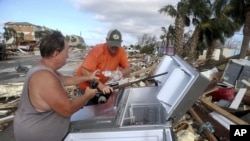 Chales Smith, izquierda, y Lee Cathey, derecha, encuentran botellas de agua en un refrigerador en medio de la US 98 en el pueblo costero de México Beach, Florida. (Douglas R. Clifford/Tampa Bay Times vía AP)