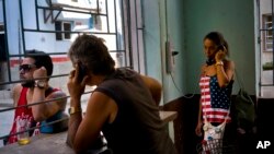 A woman uses the pay phone at a coffee shop in Havana, Cuba, March 15, 2016. With economic reforms, Cuban consumers can buy cellphones, but only one in four have them. 