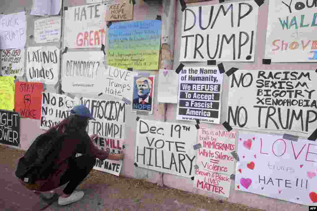 A demonstrator places a sign on a wall outside the Edward Roybal Federal Building to protest against President-elect Donald Trump in Los Angeles, Nov. 12, 2016.