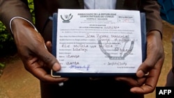 FILE - A member of the defunct M23 rebels holds an embassy form that could decide his eligibility for amnesty.