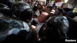 Mam Sonando (C), owner of a local independent radio station, is blocked by police officers during a demonstration in central Phnom Penh, March 31, 2014. 