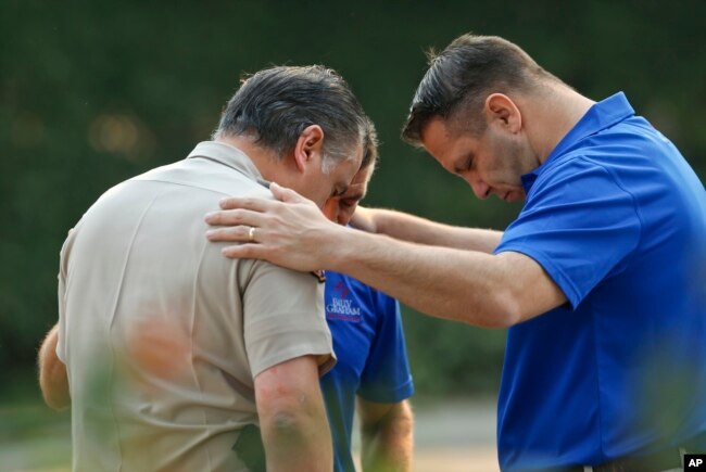 Ventura County Sheriff's Office Capt. Garo Kuredjian, left, embraces chaplains with the Billy Graham Rapid Response Team as they pray near the site of Wednesday's mass shooting in Thousand Oaks, Calif., Nov. 9, 2018. Investigators continue to work to figure out why an ex-Marine opened fire Wednesday evening inside a Southern California country music bar, killing multiple people.