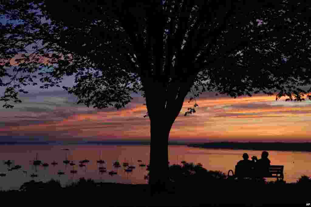 A couple enjoys a colorful sunrise over Casco Bay in Portland, Maine.