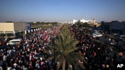 Tens of thousands of Bahraini pro-democracy protesters wave signs and national flags during a march along a divided four-lane highway near Barbar, Bahrain, west of the capital of Manama, Feb. 15, 2014. 
