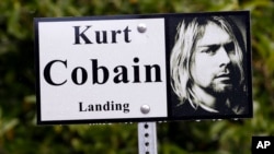 In this photo taken Monday, Sept. 23, 2013, a sign marks the location of "Kurt Cobain Landing," a tiny park blocks from the childhood home of Kurt Cobain, the late frontman of Nirvana, in Aberdeen, Wash.
