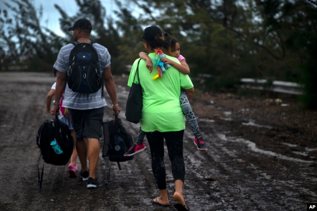 Una familia camina por una calle luego de ser rescatada cerca de Freeport, Gran Bahama, el martes 3 de Septiembre de 2019. AP