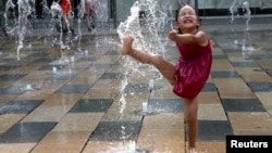 一個北京小女孩在暑熱天裡玩水沖涼。（2017年7月12日） 
