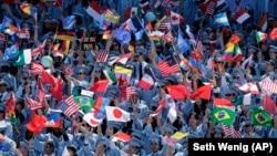 Graduating students from the School of International and Public Affairs at Columbia University hold flags during a graduation ceremony.