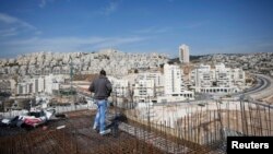 Laborer stands on apartment building construction site in Jewish settlement known to Israelis as Har Homa and to Palestinians as Jabal Abu Ghneim, West Bank, Oct. 28, 2014.