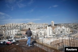 FILE - A laborer stands at apartment building construction site in Jewish settlement known to Israelis as Har Homa and to Palestinians as Jabal Abu Ghneim, West Bank, Oct. 28, 2014.